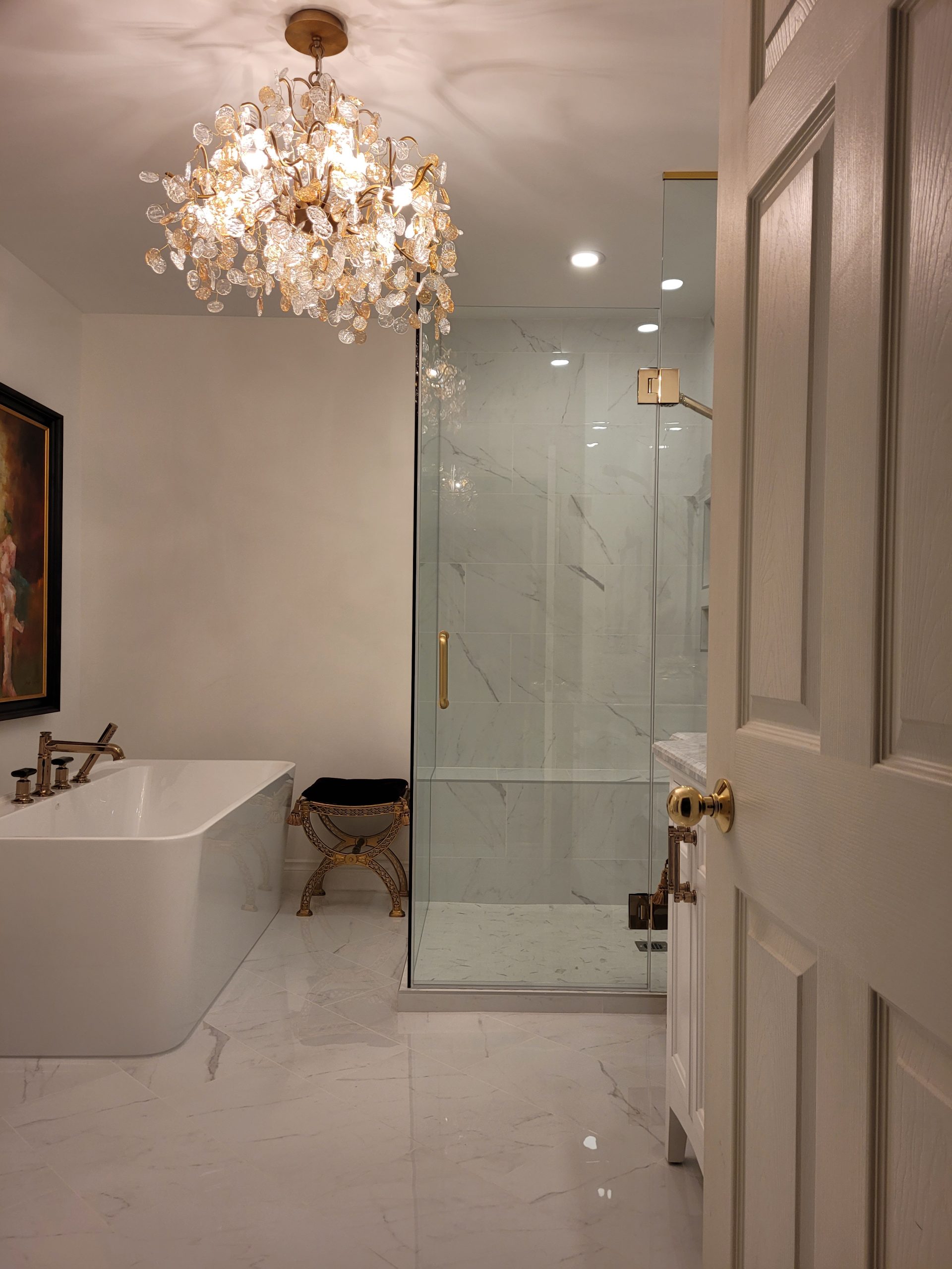 Completed Calgary ensuite bathroom with a freestanding tub, glass shower, vanity, and chandelier